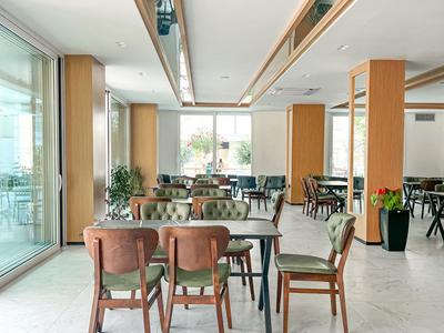 Moderner Hotelrestaurantbereich mit Holztischen, Stühlen und großen Fenstern