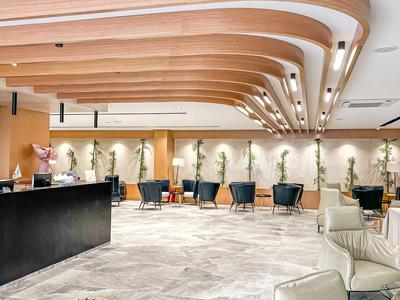 Moderner Hotel-Loungebereich mit geschwungener Holzdecke und Sitzgelegenheiten.