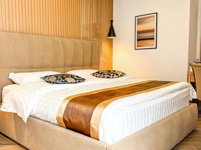 Modernes Hotelzimmer mit großem Bett, dekorativen Kissen und warmem Beleuchtungselement an der Wand.