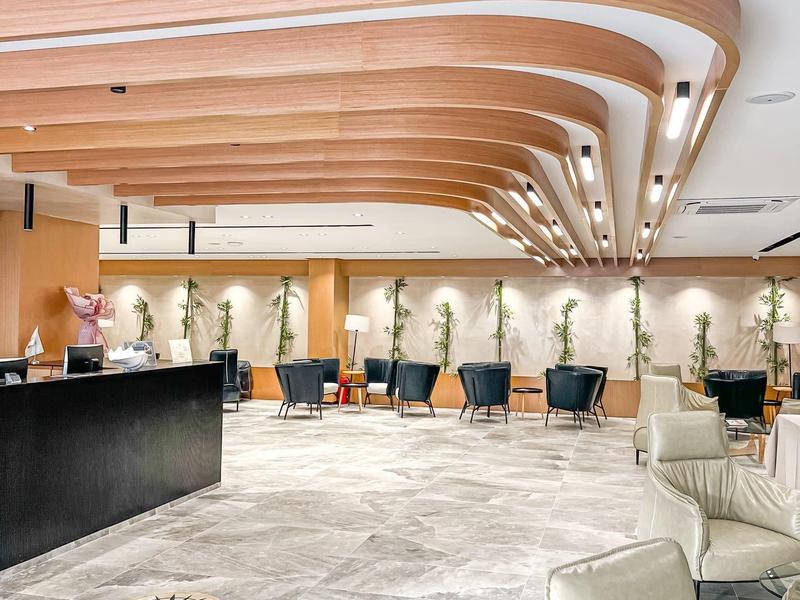 Hotel-Lobby mit modernem Holzdecken-Design, Steinskulpturen und bequemen Sesseln.