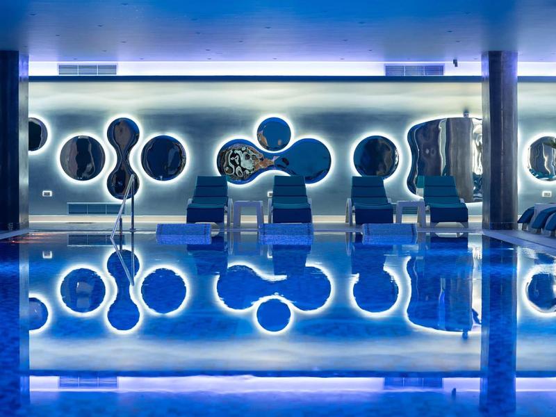 Moderner Poolbereich mit futuristischen Sitzgelegenheiten und blauer Beleuchtung.