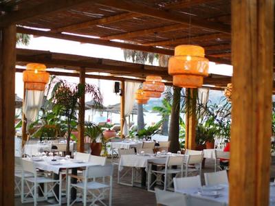 Überdachter Außenbereich eines Restaurants mit weißen Tischen und Pflanzen.