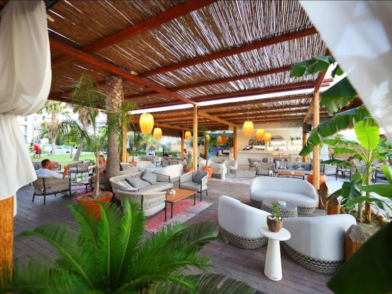 Gemütliche Außenlounge mit bequemen Sofas und Pflanzen unter einem Holzpergola-Dach.