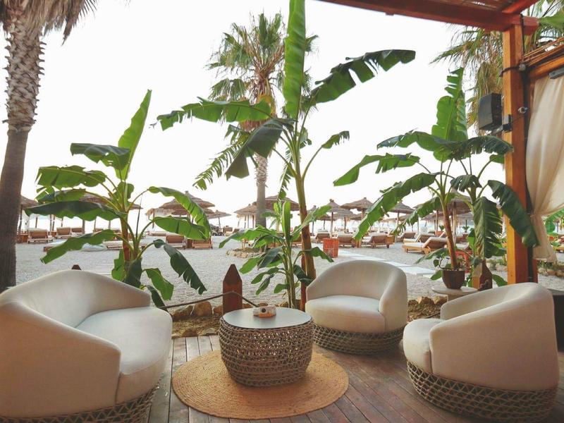 Gemütliche Loungesessel unter einem Pavillon mit tropischen Pflanzen und Strandblick.