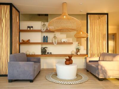 Bright hotel lounge area with two armchairs, round table, and decorative shelves on the wall.