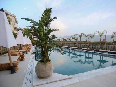 Moderner Poolbereich mit Liegestühlen und Pflanzen in einem Hotelresort.