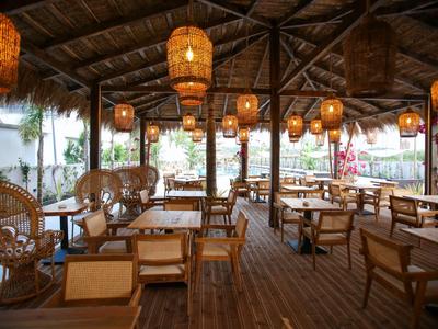 Offener Restaurantbereich mit Holzdecke, Korbstühlen und warmen Hängelampen.