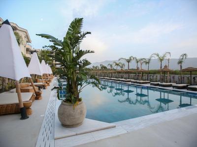 Nowoczesny basen hotelowy z leżakami i parasolami pod błękitnym niebem.