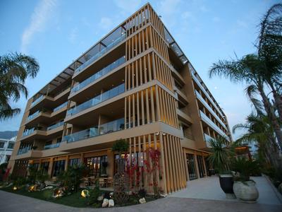 Moderner mehrstöckiger Hotelbau mit Balkonen und Palmen bei blauem Himmel.