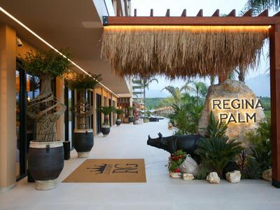 Eingangsbereich eines tropischen Resorts mit Pflanzen, Schilfdach und dekorativen Objekten.