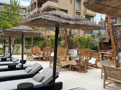 Taras hotelowy z leżakami i parasolami z naturalnych materiałów.