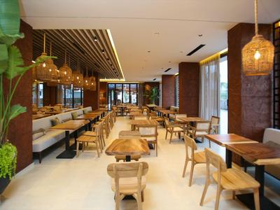 Moderner Speisesaal mit Holztischen, Stühlen und Pflanzen, warmes Ambiente.