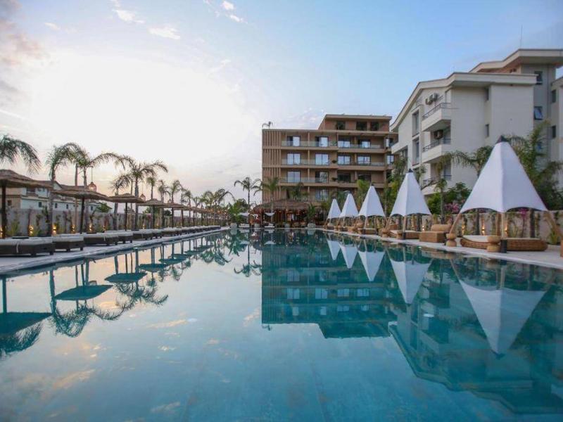 Moderner Hotelpool mit Liegestühlen und Sonnenschirmen bei Sonnenuntergang.