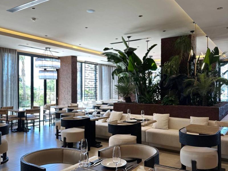 Modernes Hotelrestaurant mit gemütlichen Sitzbereichen und großen Pflanzenarrangements.