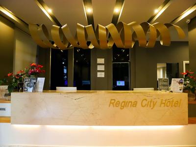 Moderner Hotelempfang mit beleuchtetem Tresen und dekorativer Deckeninstallation.