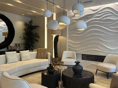 Lounge d'hotel moderna con poltrone luminose, tavoli rotondi e decorazione murale ondulata.