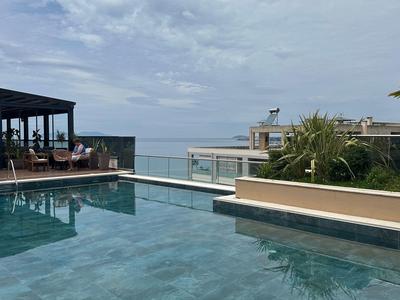 Piscina all'aperto moderna con vista sul mare e zona salotto sotto cielo nuvoloso