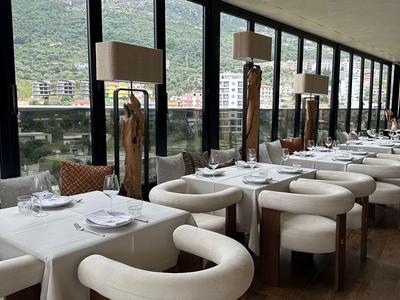 Ristorante d'hotel moderno con sedute bianche e ampie finestre panoramiche con vista sulle montagne.