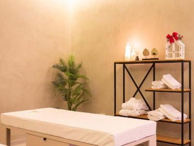 Sala de masajes luminosa y moderna con mesa, estantería y planta decorativa