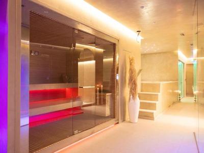 Zona de spa moderna con baño de vapor iluminado y pasillo luminoso.