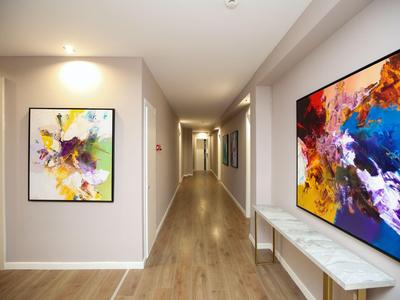 Moderner, gut beleuchteter Hotelflur mit abstrakter Kunst an den Wänden und Holzfußboden.