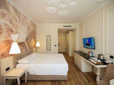 Helles Hotelzimmer mit Doppelbett, Wandkunst, Fernseher und Holzfußboden.