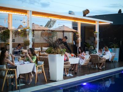 Abendessen im Freien an einem eleganten Hotelpool mit gedeckten Tischen und Gästen.