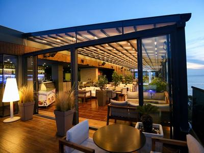 Gemütliche Hotelterrasse mit modernen Möbeln und Glasüberdachung bei Abenddämmerung