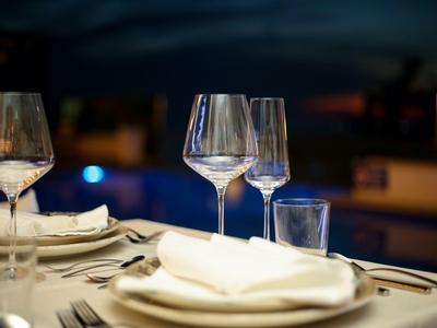 Eleganter gedeckter Tisch mit Weingläsern und weißen Servietten in einem Restaurant bei Nacht.