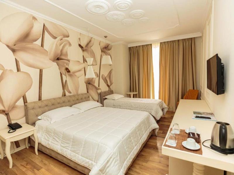 Helles Hotelzimmer mit zwei Betten, weißer Bettwäsche und modernem Schreibtisch.