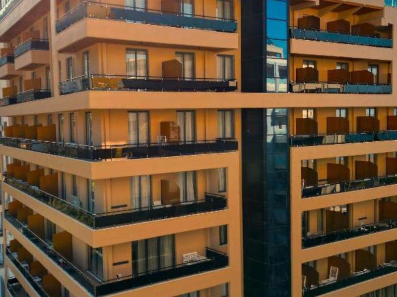 Moderner mehrstöckiger Hotelgebäudekomplex mit Balkonen und Glasgeländern bei Sonnenuntergang.