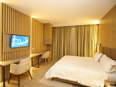Modern eingerichtetes Hotelzimmer mit Holzwand, Doppelbett und Fernseher an der Wand.