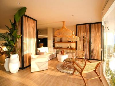 Hell eingerichteter Lounge-Bereich mit Sesseln, Kamin und großen Fenstern mit Blick ins Freie.