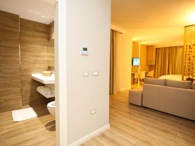 Helles Hotelzimmer mit Sitzecke und modernem Badezimmer mit Holzfliesen.