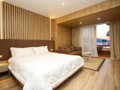 Hell eingerichtetes Hotelzimmer mit großem Bett, Sitzbereich und Balkon mit Meerblick.