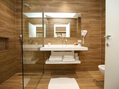 Modernes Badezimmer mit Holzoptikfliesen, großem Spiegel und weißem Waschbecken.