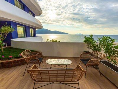 Balkon mit Sitzgruppe und Blick auf das Meer bei bewölktem Himmel.