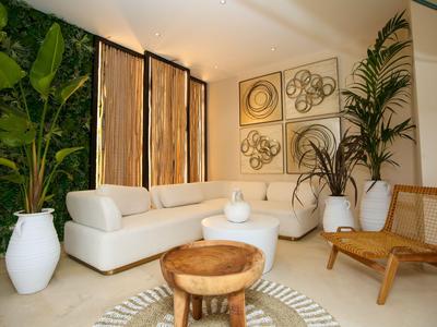 Helles Wohnzimmer mit weißem Sofa, Holztisch, Pflanzen und moderner Wanddekoration.