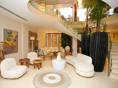 Helles und modernes Wohnzimmer mit weißem Möbelensemble, hölzernen Beistelltischen und großer Vase.