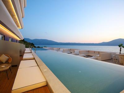 Moderner Infinity-Pool mit Sonnenliegen und Bergblick bei Sonnenuntergang.