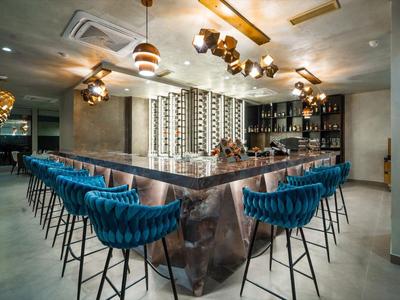 Nowoczesny bar z niebieskimi stołkami i stylowym oświetleniem w hotelu.