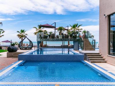 Nowoczesny basen na zewnątrz z wiszącymi ogrodami i parasolami obok budynku hotelowego