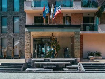 Wejście do hotelu z fontanną, schodami i trzema flagami nad drzwiami.