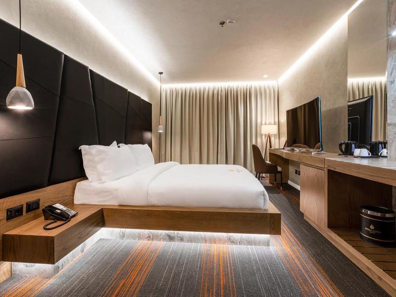 Modernes Hotelzimmer mit Doppelbett, Schreibtisch und indirekter Beleuchtung