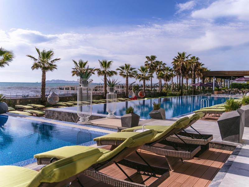 Luxuriöser Außenpool mit Liegestühlen und Meerblick unter blauem Himmel
