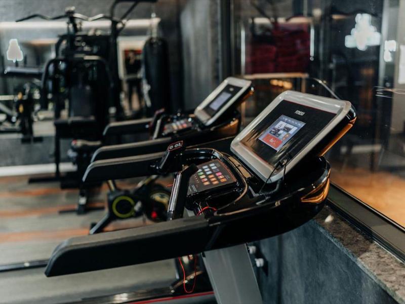 Moderne Fitnessgeräte mit Touchscreens in einem stilvollen Fitnessstudio im Hotel.