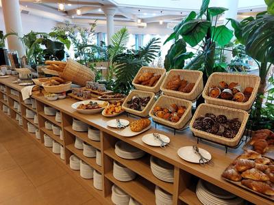 Buffet mit verschiedenen Backwaren und Gebäck in einer Pflanzenumgebung.