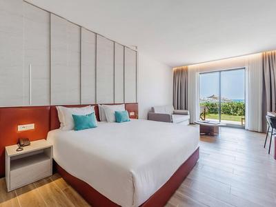 Modernes Hotelzimmer mit großem Bett, Sitzbereich und Blick auf den Garten.