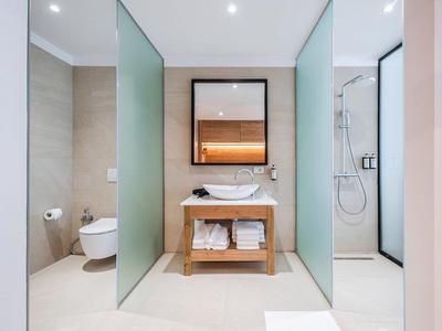 Modernes Badezimmer mit Waschbecken, Spiegel, freistehender Toilette und Dusche mit Glaswänden.