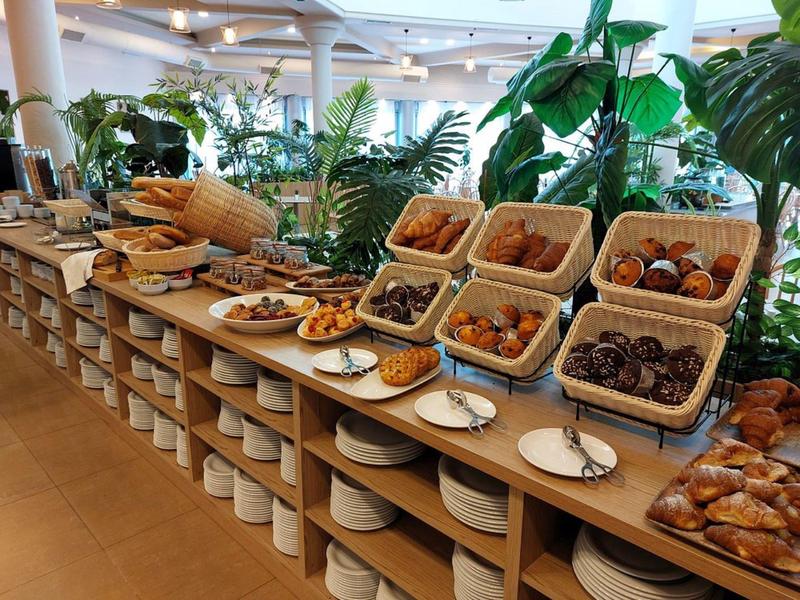 Buffet mit verschiedenen Backwaren und Gebäck in einer Pflanzenumgebung.